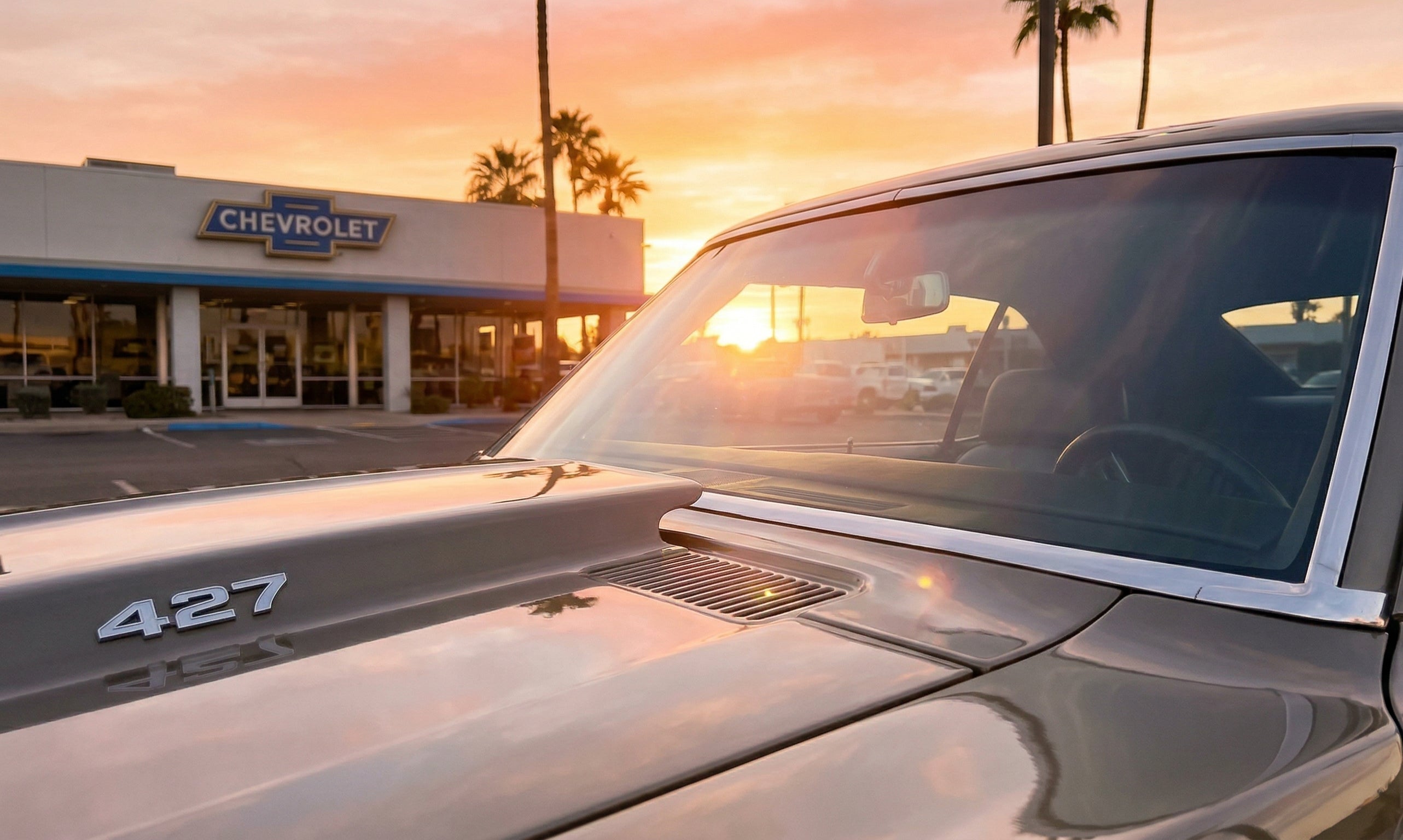A 1969 Chevrolet Camaro finished in the style of a Yenko COPO 427 car, photographed outside a shop at golden hour