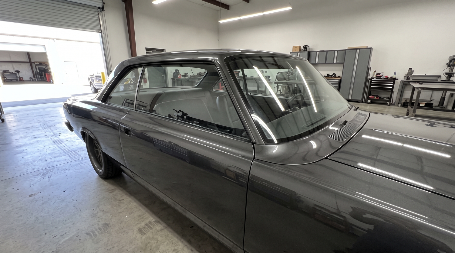 Pro-touring classic muscle car in a Phoenix shop with doors closed and flush-mount glass, representing a finished fiberglass door panel interior build