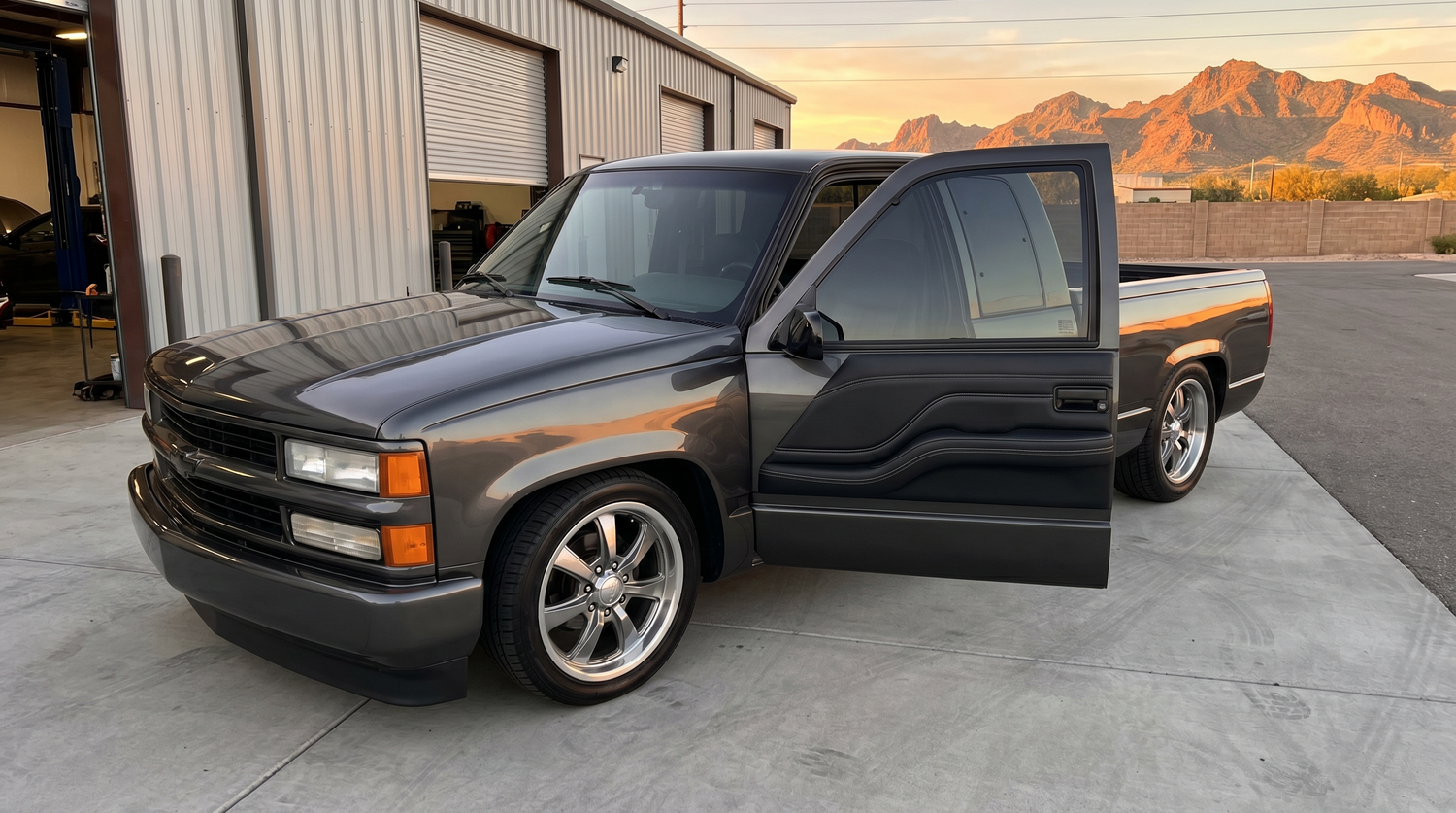 Lowered OBS Chevy truck with door open showing a smooth custom fiberglass door panel at golden hour in Phoenix